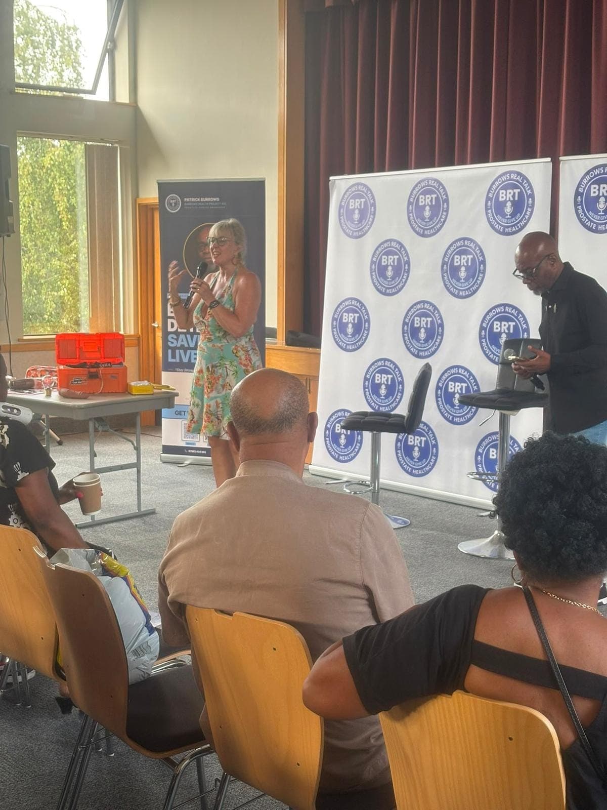 Lorraine Grover speaking while Patrick Burrows holds a microphone.