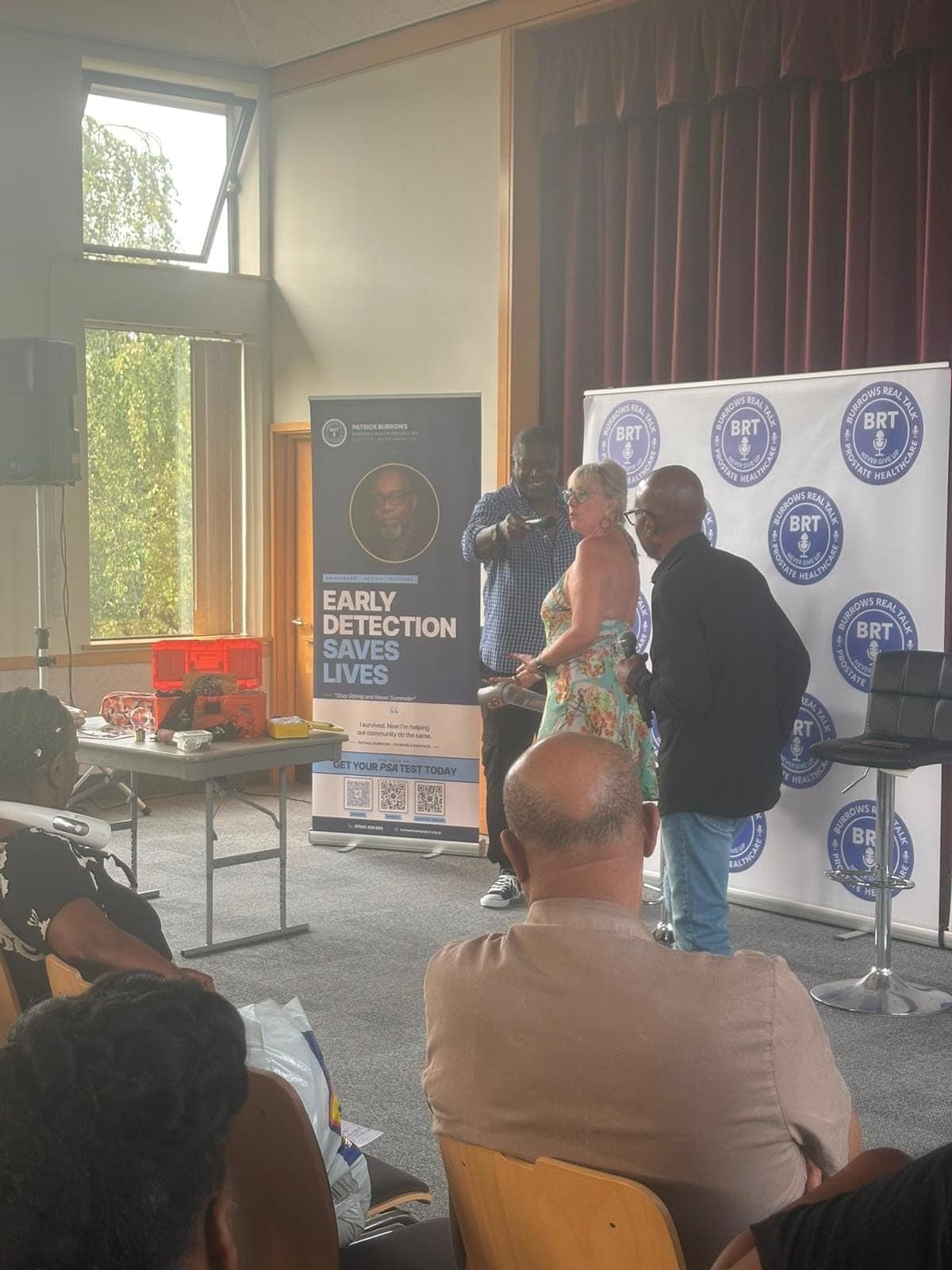 Lorraine Grover and Patrick Burrows with a photographer beside the event banner.